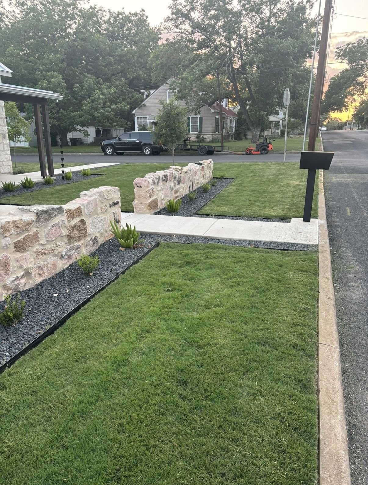 Stone wall, gravel borders, and native plantings along a front sidewalk